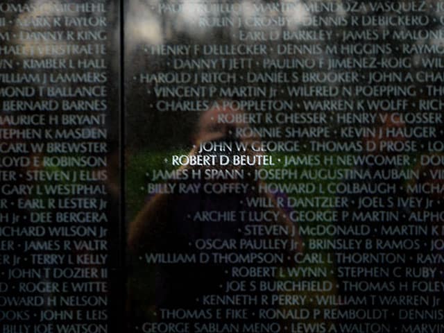 A photo of the Vietnam Veterans Memorial in Washington DC showing Bob Beuel's name is highlighted.