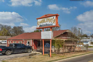 A Chelinos truck is parked in front of a restaurant.