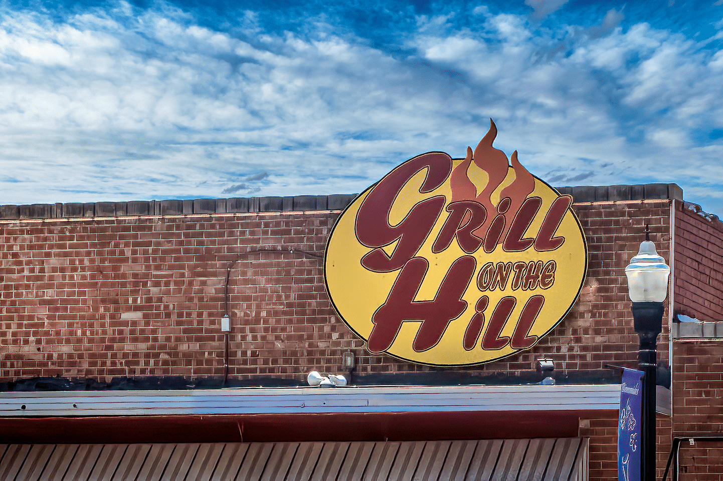 A brick building featuring a prominent sign displaying "grill on the hill.