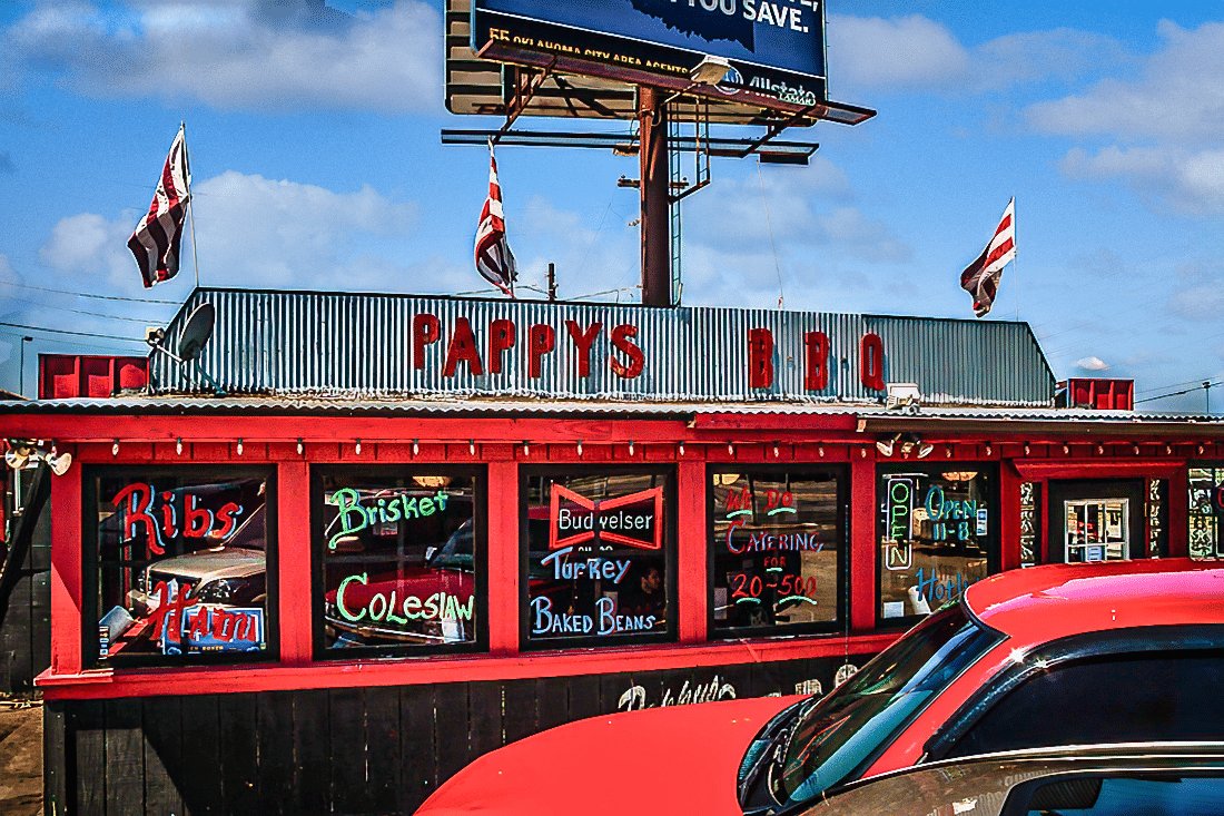 A red car parked in front of Pappy's BBQ.