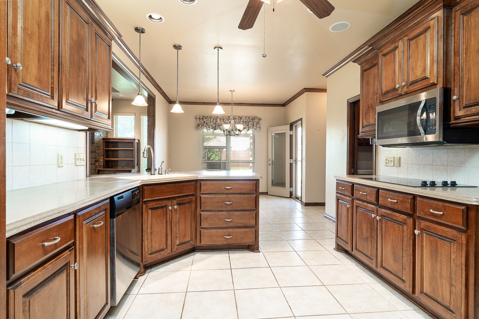 A kitchen with wooden cabinets and a ceiling fan.