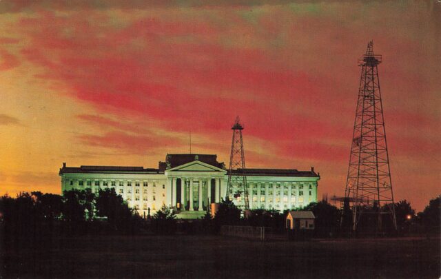 The Oklahoma State Capitol building shown with a red sunset behind and the state capitol oil derricks in front.