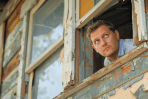 A forlorn home seller looking out his window. Common mistakes made by first time home sellers.