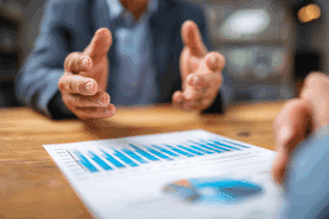 A person in a suit gestures with their hands while discussing the effect of mortgage interest rates.