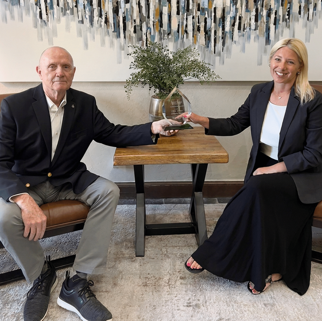 Bill Wilson and Heather Wall of OKCHomeSellers seated together with a McGraw Realtors award.